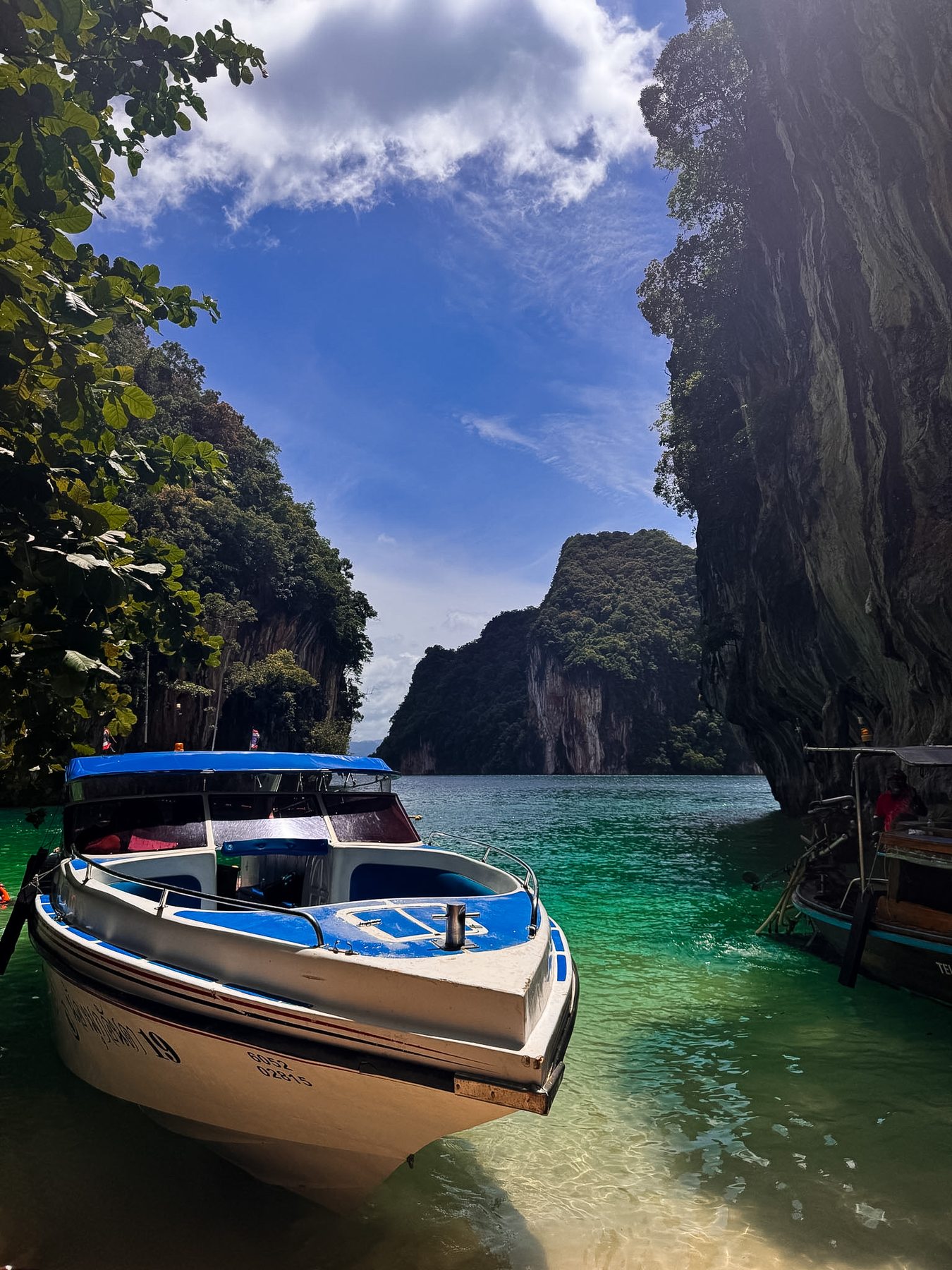 Longtail boats in a turquoise lagoon between limestone cliffs, Thailand