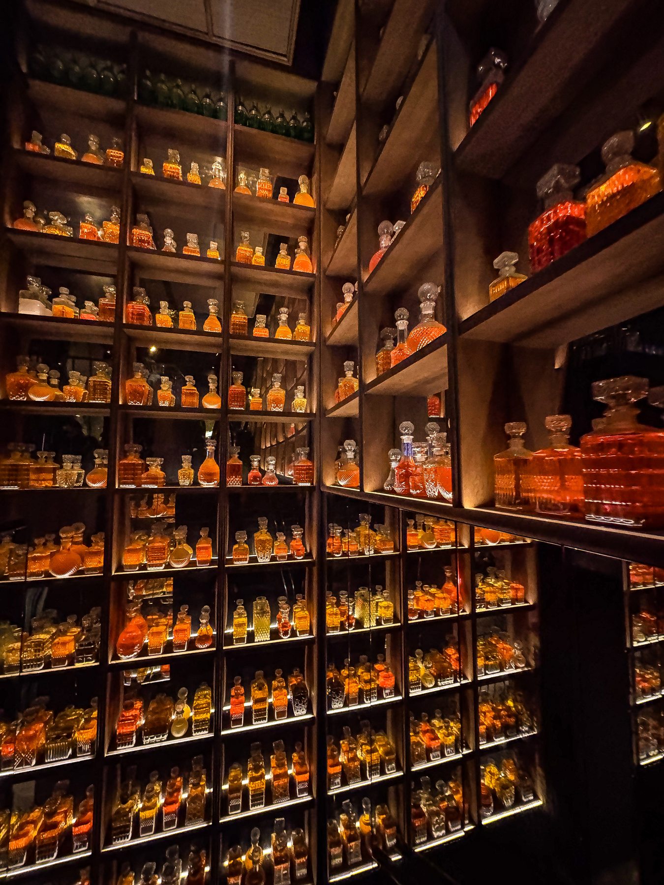 Wall of amber glass decanters lit from below