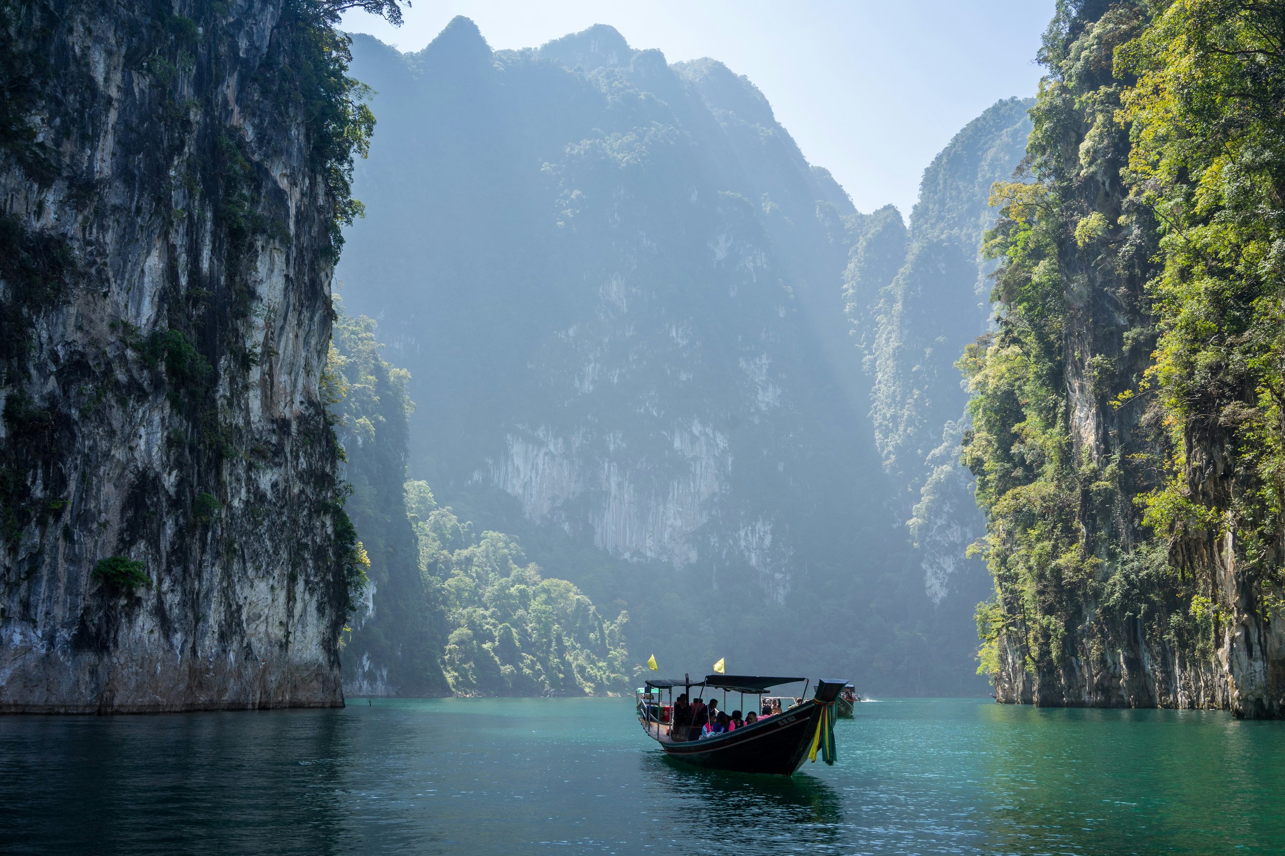 Longtail boat in a turquoise lagoon between limestone cliffs